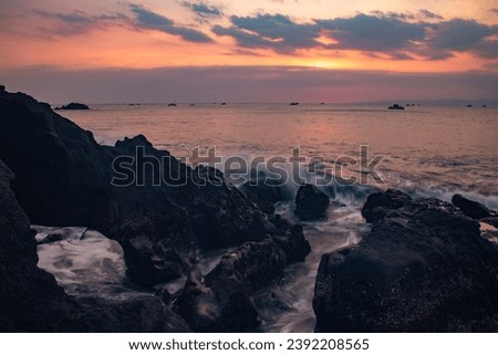 Beautiful beach view at sunset. rocks on the beach. Waves captured with a slow shutter speed. Long exposure with soft focus. Sky with clouds. Loh Ji Beach, West Java, Indonesia