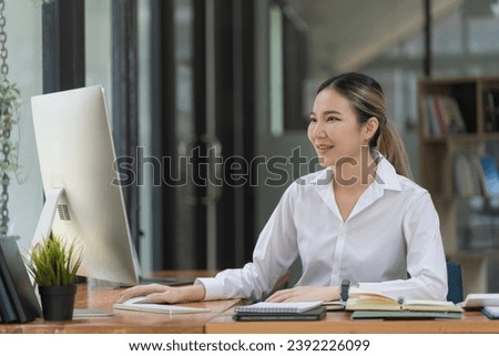 Portrait of a beautiful Asian businesswoman using a desktop computer, businesswoman managing company operations, analyzing statistics, commerce data, and marketing plans.