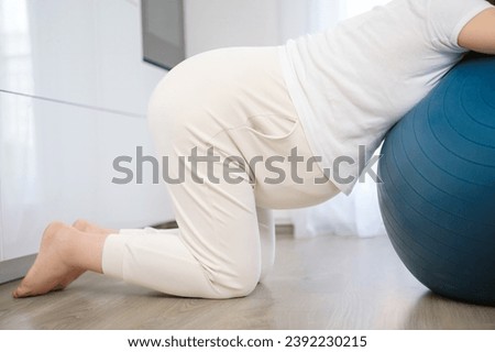 Pregnant woman resting on fitball during contractions at home. H