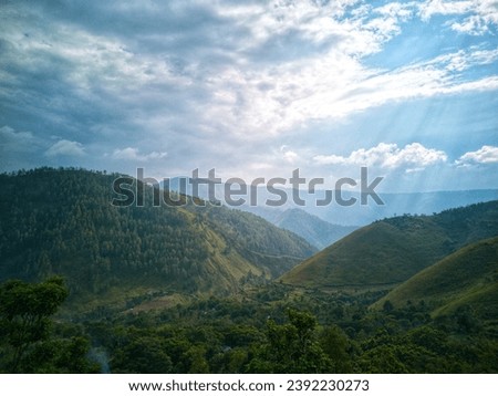 Tranquil scene in a peaceful forest valley with mountain range and sun rays.