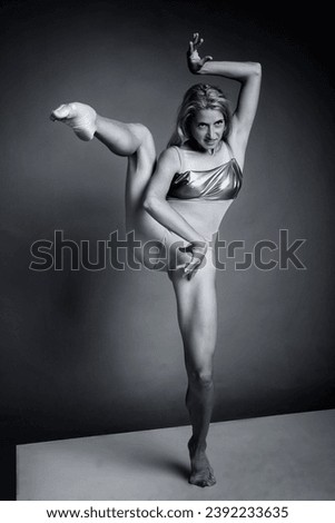 a ballerina in a bodysuit stands on one leg supporting the other leg raised up with one hand