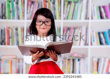 Picture of adorable schoolgirl with opened book in a library
