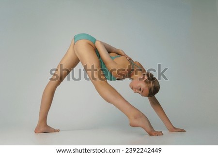 a young ballerina in a bodysuit stands in a lunge leaning forward with one foot on the toe