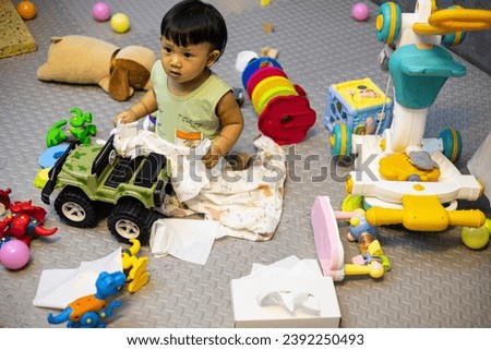 A mess in the children's room, a lot of toys in the children's room. Dirty house. Adorable toddlers playing among the many toys at home.