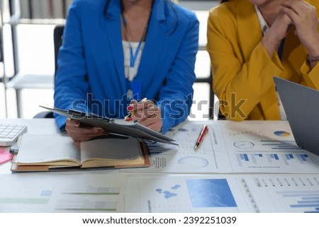 Asian business colleagues present and discuss investment project work and planning strategies. Budget calculation Income from documents reporting the company's business growth.