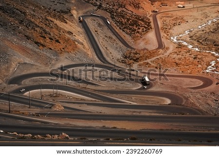 Cars trucks and lorries driving on the twisting and turning switchback road through high Andes in Chile, South America Royalty-Free Stock Photo #2392260769