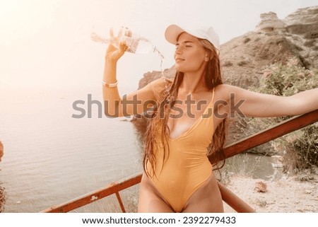 Woman travel sea. Happy tourist enjoy taking picture outdoors for memories. Woman traveler drinks water at the edge of the cliff on the sea bay of mountains, sharing travel adventure journey