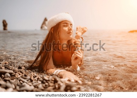 Woman travel sea. Happy tourist enjoy taking picture on the beach for memories. Woman traveler in Santa hat looks at camera on the sea bay, sharing travel adventure journey