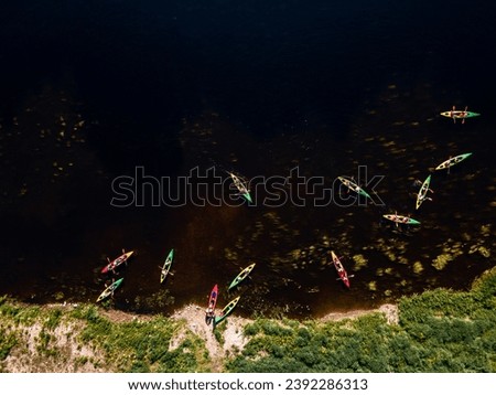 Group of colorful kayaks in a row on a dark water river with surrounding greenery