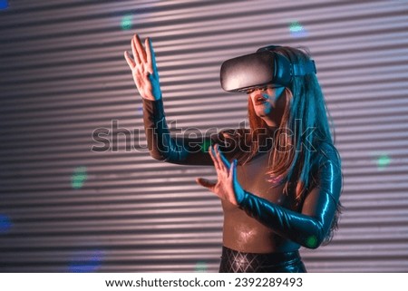 Woman wearing a VR goggles and gesturing raising arms in an futuristic night space with neon lights
