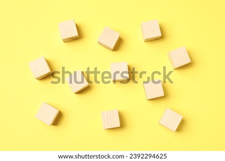 Many empty wooden cubes on yellow background, flat lay