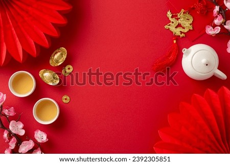 Lunar New Year tea ceremony top view setting featuring Feng Shui elements, teapot set, and green tea for a family ritual. Paper fans and orchids adorn the red backdrop, creating a festive atmosphere