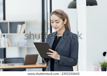Portrait of Asian businesswoman using digital tablet standing in office workplace.