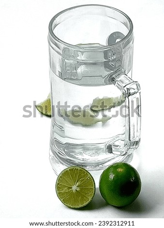 SHOTLIST health green lime and water in a glass jar placed on a white background. Lime helps relieve headaches. Close -up shot of them.