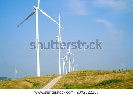 White windmill in green field. Bright sky