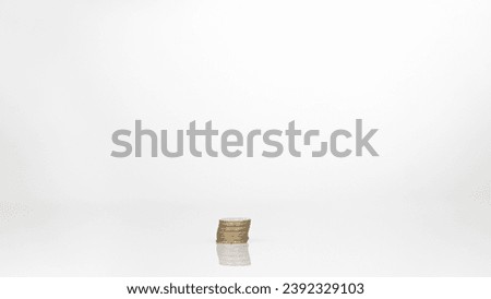 Coins are arranged in high and low shelves, mixed together. There is a reflection on the floor. Shows the value of money in today's economy. The background of the picture is white.