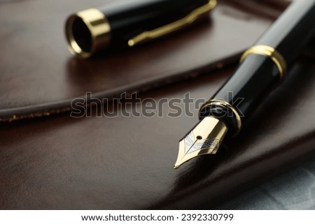 Stylish fountain pen, cap and leather notebook on grey table, closeup Royalty-Free Stock Photo #2392330799