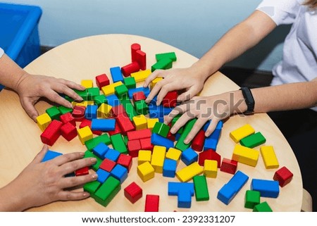 Hands of an adolescent patient and her psychotherapist playing with colored wooden blocks in therapy. Concept of therapy and mental health