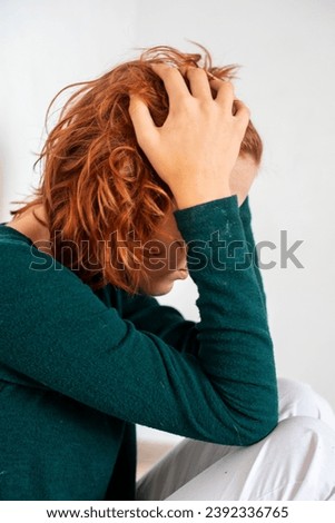 close-up portrait of a beautiful teenage girl with red anime hair clutching her head on a light background