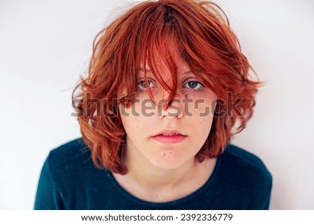 portrait of a beautiful teenage girl with red anime hair on a light background