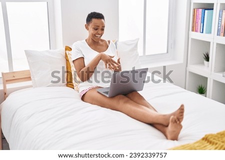 African american woman having video call sitting on bed at bedroom