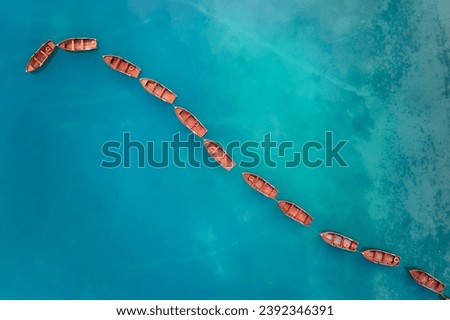 An artistic, perpendicular view of an axis shape made of wooden boats on the blue-green surface of Lago di Braies in the Dolomites. Ideal for poster projects.