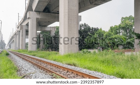 A picture of a railroad running diagonally from right to left as far as the eye can see. The racetrack area is quite old and rusty. On both sides of the road there were medium sized rocks and green gr