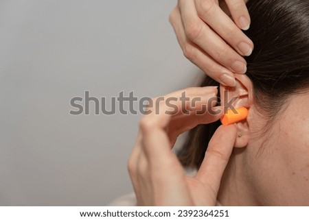 Woman Inserting Earplug for Hearing Protection Royalty-Free Stock Photo #2392364251