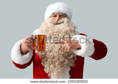 Santa Claus pointing at mug of beer on white background