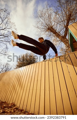 Fish eye effect photo of young man, guy performing insane tricks and breathtaking flips over wall in motion. Extreme sport activity, free running. Concept of lifestyle, sport, freestyle, activity.
