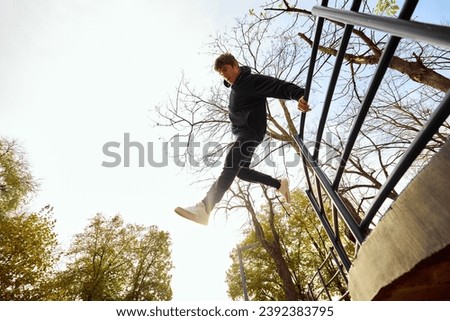 Athlete man, young guy jumps over parking lot, practice Parkour in public park among over sky view. Eye fish filter. Concept of lifestyle, extreme kinds of sport, freestyle, activity, motion. Ad