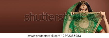 pretty indian woman with bindi dot on forehead covering face with green veil looking away, banner