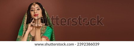 beautiful indian woman with bindi dot posing with hands near face and looking at camera, banner