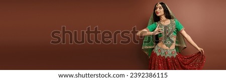 beautiful indian woman with bindi dot in traditional attire gesturing while dancing lively, banner
