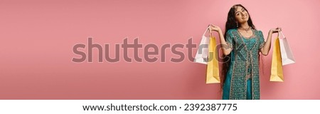 cheerful indian woman in national costume posing with shopping bags and smiling at camera, banner