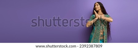 cheerful indian woman in blue sari with accessories posing in motion on purple backdrop, banner