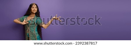 cheerful indian woman in traditional clothing gesturing while dancing on purple backdrop, banner