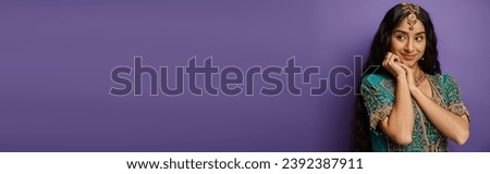 jolly indian woman in national costume with accessories posing on purple background, banner