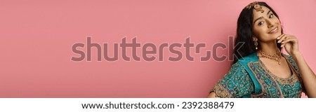 cheerful indian female model with accessories in blue sari posing with hand near face, banner