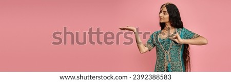 beautiful jolly indian woman in national costume gesturing and looking away on pink backdrop, banner