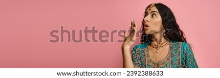 shocked attractive indian woman in traditional blue sari posing with hand near mouth, banner