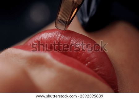Macro photo process of applying permanent makeup tattoo of red on lips woman