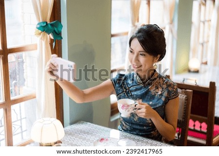 Traditional chinese woman wear cheongsam and use cellphone to take photo in tea house