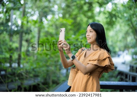 Woman use mobile phone to take photo in the park