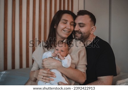 Smiling mother and father holding their newborn baby son at home