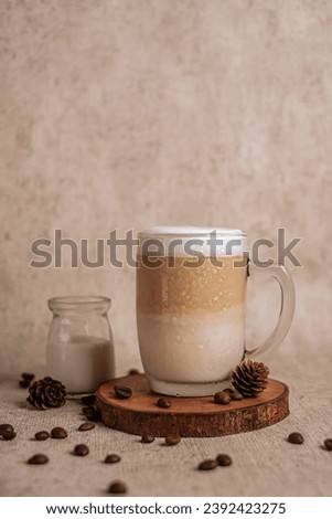 Iced caramel latte topped with foam, refreshing and sweet coffee drink, creative desk