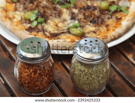Chilli flakes and Oregano in front of Pizza.jpeg