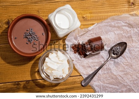 Chocolate panna cotta with coconut milk, vegan chocolate pudding with agar-agar and extra-dark cocoa powder. Coconut milk, cocoa powder, chips and dry lavender next to a delicious Italian dessert Royalty-Free Stock Photo #2392431299