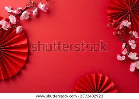Lunar New Year vibes captured: Overhead shot featuring fans, Feng Shui essentials, and sakura blooms on a crimson backdrop, leaving space for messages or ads
