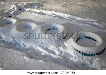 Snow-covered old tires lie on the ground on a winter day